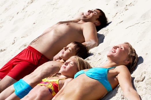 Photo of happy family lying on sand and sunbathing