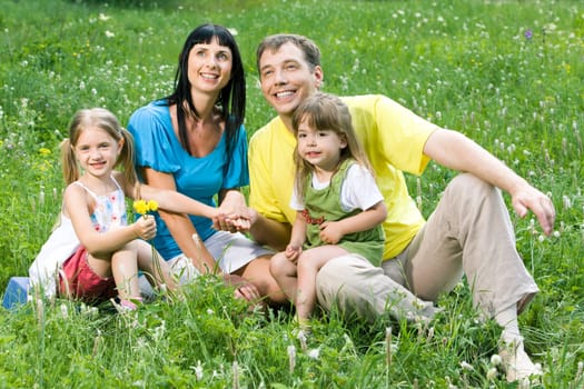 Portrait of little girl giving flower to her mother with father and sister near by