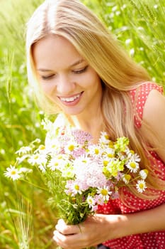 Portrait of young woman holding bunch of flowers outside