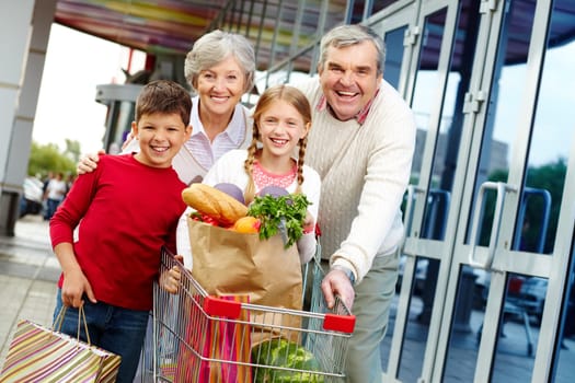 Portrait of happy grandparents and grandchildren near supermarket