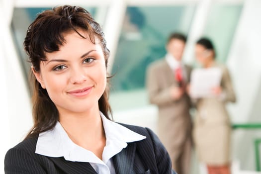Portrait of pretty business leader in working environment looking at camera