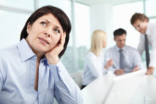 Mature businesswoman at workplace thinking about something in working environment