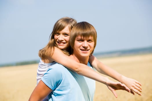 Portrait of handsome man holding his girlfriend on his back