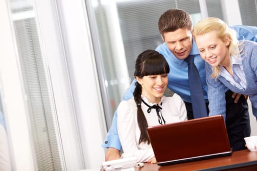 Three businesspeople looking at a laptop in the office