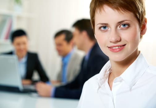 Close-up of young office worker with her colleagues in the background