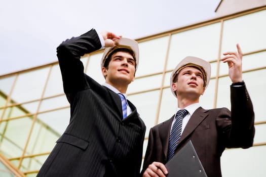 Photo of two co-workers discussing work while one of them showing something to colleague