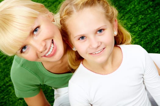 Portrait of happy woman embracing her pretty daughter and both looking at camera