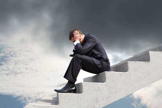 Image of pensive businessman sitting on stairs against thunderclouds
