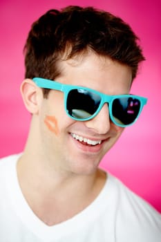 Handsome man with print of lipstick on his cheek and glamorous sunglasses