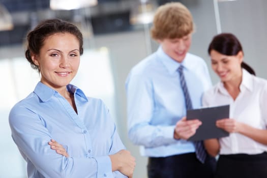 Portrait of friendly specialist looking at camera on the background of colleagues