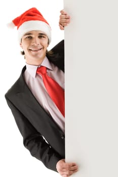 Photo of businessman in santa cap peeking out of blank poster and smiling