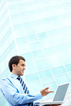 Young businessman using computer by office building