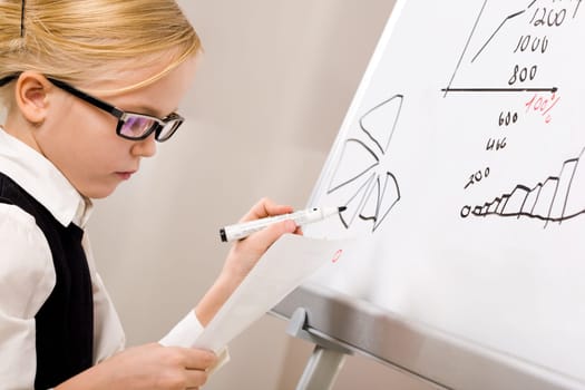 Portrait of smart girl with pen in hand standing by whiteboard