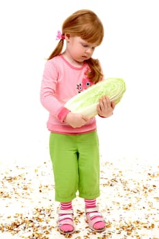 Portrait of serious girl holding Chinese cabbage and looking at it