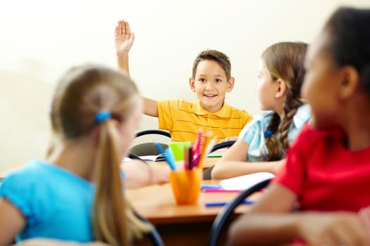 Image of smart pupil raising arm during the lesson