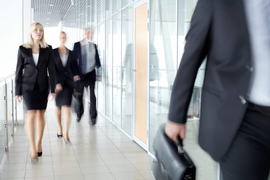 Business people walking along the office corridor
