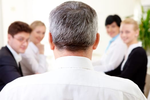 Rear view of aged businessman making report to partners at conference
