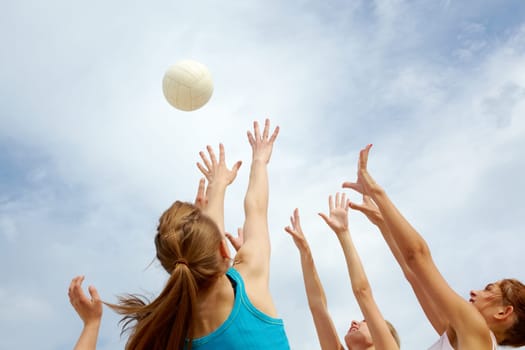 Photo of teenage friends playing with ball on background of cloudy sky