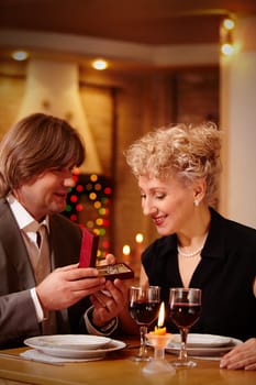 Image of handsome man making proposal to beautiful woman while holding small open box before her