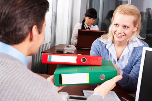 Pretty secretary giving papers to boss in the office
