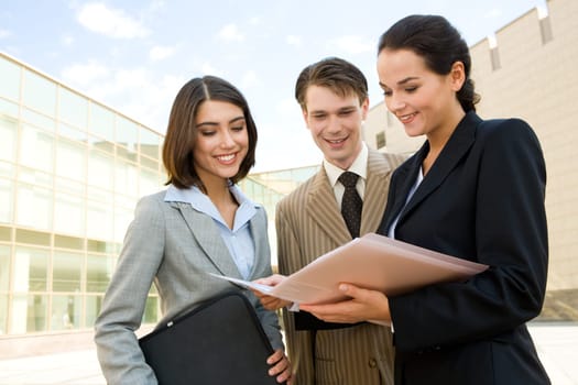 Portrait of business group discussing new plans in womans hands outdoors on background of modern building