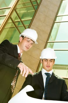 Portrait of two confident workers discussing a project near building