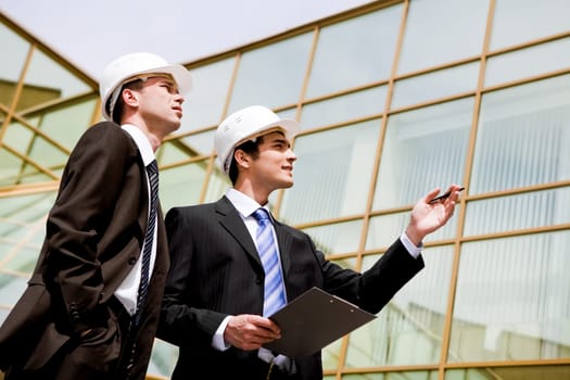 Photo of two co-workers looking at new building while one of them pointing at it
