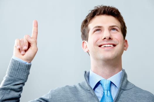 Image of young handsome businessman looking upwards with raised forefinger