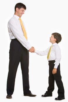 Portrait of father and son standing and handshaking while looking at each other on white background