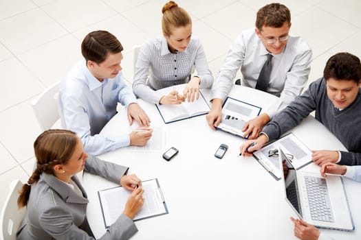 Image of company of successful partners looking at their colleague at meeting