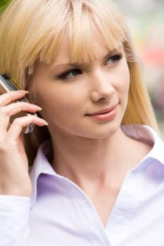Portrait of pretty woman speaking on mobile and looking aside with smile