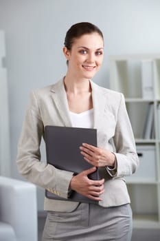 Portrait of smiling businesswoman with folder looking at camera in office