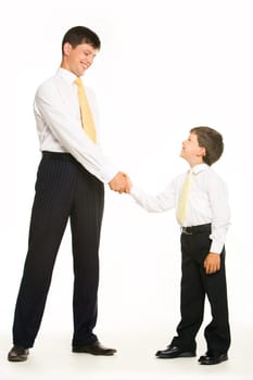 Portrait of father and son standing and handshaking while looking at each other on white background