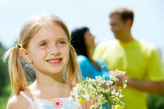 Face of cheerful girl looking aside with smile on background of her father and mother