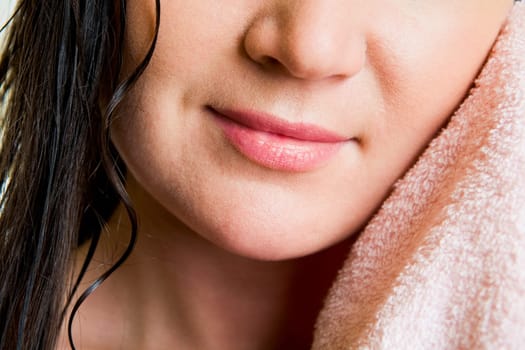 Lower part of female face drying herself with soft towel
