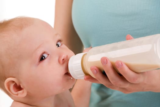 Face of adorable baby looking at camera while drinking milk