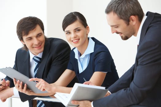 Pretty business lady looking at camera with smile surrounded by her co-workers