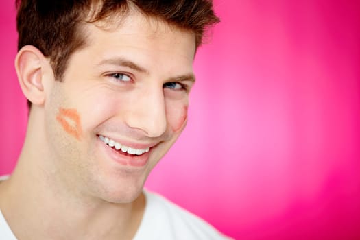 Handsome man with print of lipstick on his cheek smiling at camera