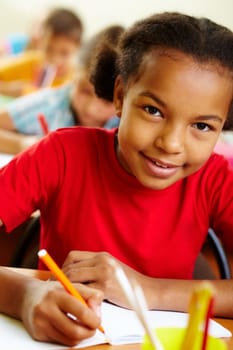 Portrait of lovely girl drawing with crayons at lesson