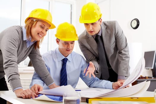 Three architects sitting at table and looking at a project