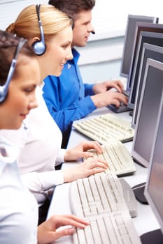 Row of telephone operators looking at the monitors and working