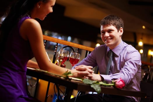 Portrait of amorous couple holding by hands in the cafe