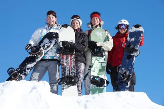 Portrait of happy company of guys and girl with snowboards