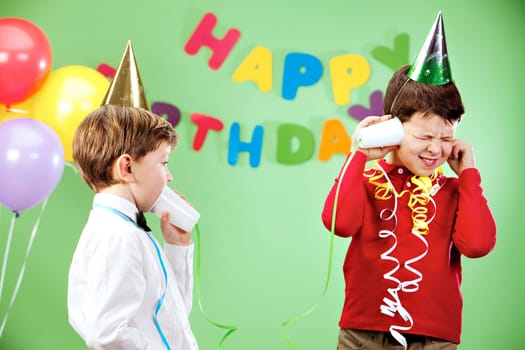 Portrait of happy boys playing with plastic glasses on birthday party