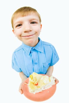 Portrait of little boy with cake in hands looking at camera over white background