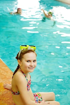 Photo of happy girl in swimming pool smiling at camera