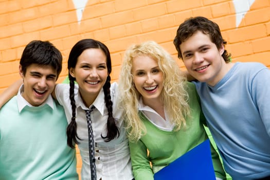 Portrait of laughing friends standing next to each other and looking at camera