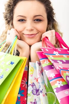 Closeup of young girls face looking at camera with smile and holding paper bags with presents