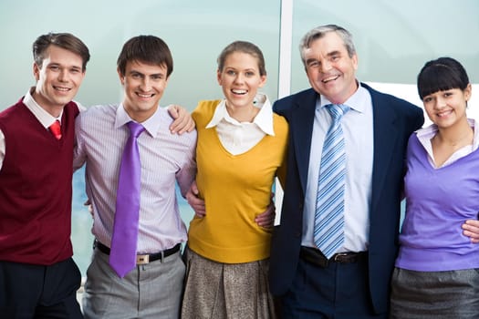 Portrait of happy colleagues embracing and looking at camera with smiles