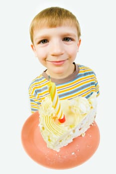 Photo of saucer with a piece of birthday cake on it on the background of cute boys face looking at camera